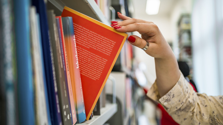 A person taking book off of a library shelf