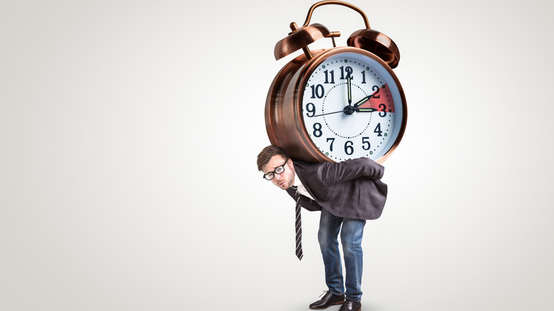 a man with a clock on his back struggling with Daylight Savings Time change