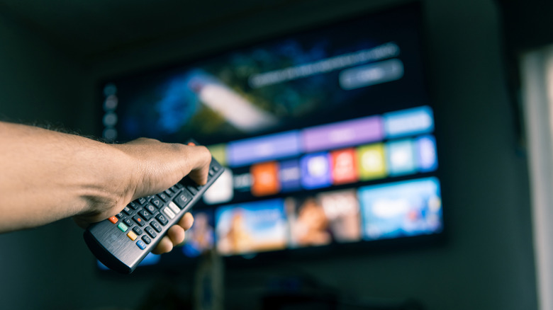 A person using a remote controller with their TV.