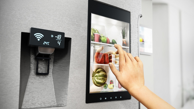 A person using a touchscreen on a smart fridge.