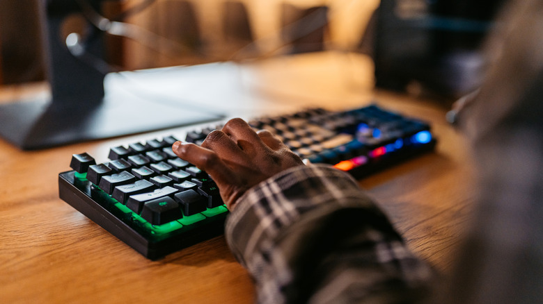 A person playing a game using a backlit mechanical keyboard.