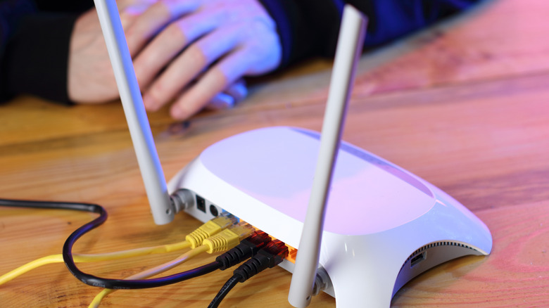 A person using a travel router on a flat wooden surface.