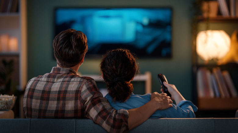 A couple on a sofa watching a movie in their living room