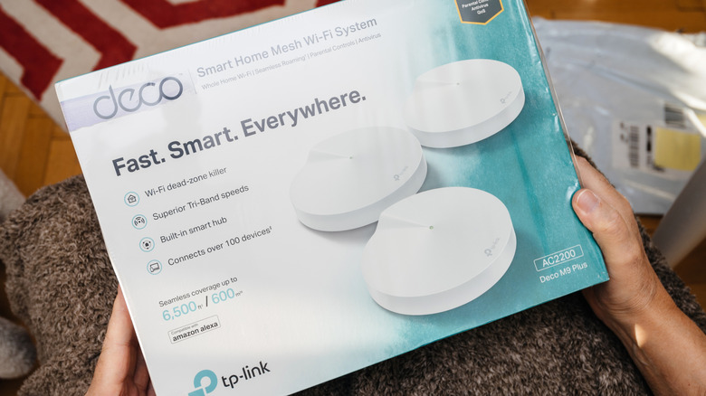 Close-up of a person holding a tri-band mesh Wi-Fi system from TP-Link