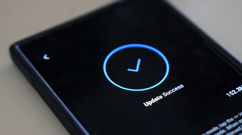 Close-up of a smartphone displaying a success message on the screen after a system update.