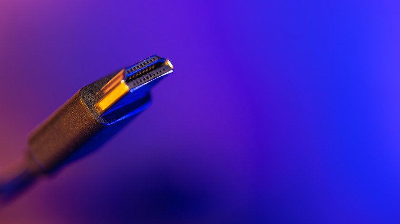 An HDMI cable set against a purple backdrop.