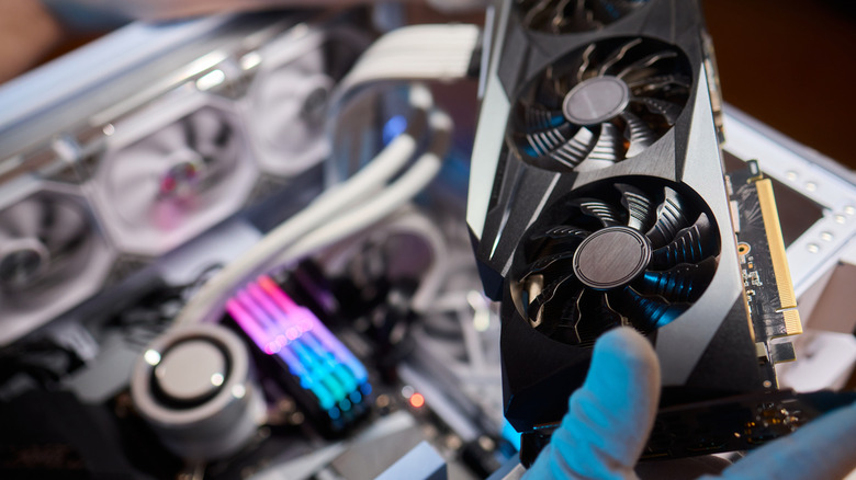 Hand holding a GPU with a PC in the background