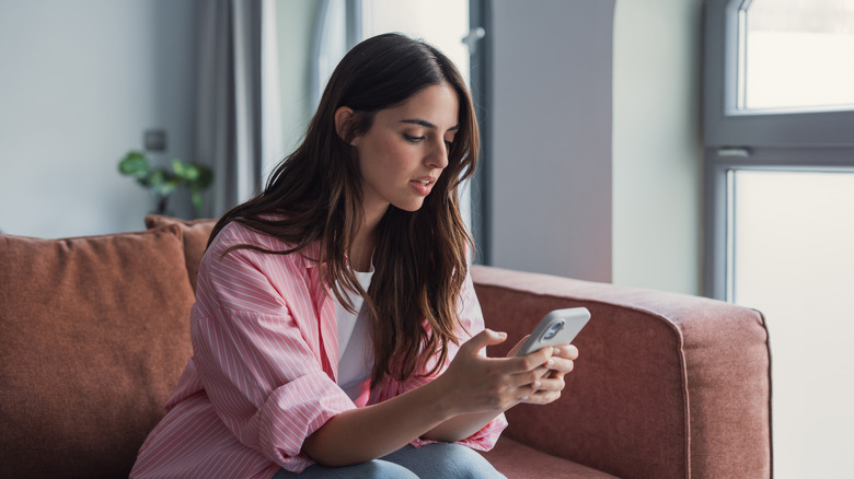 A woman looking at her phone with a frustrated expression on her face, potentially due to a slow or faulty internet connection