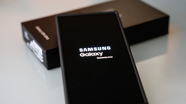 Samsung Galaxy laid outside of the box showing the Samsung logo displayed on the phone