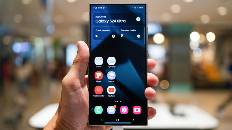 a person holding up a Samsung Galaxy S24 Ultra while at a store