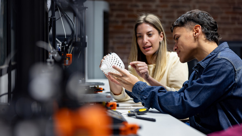 People examining a 3D printed piece and discussing it.