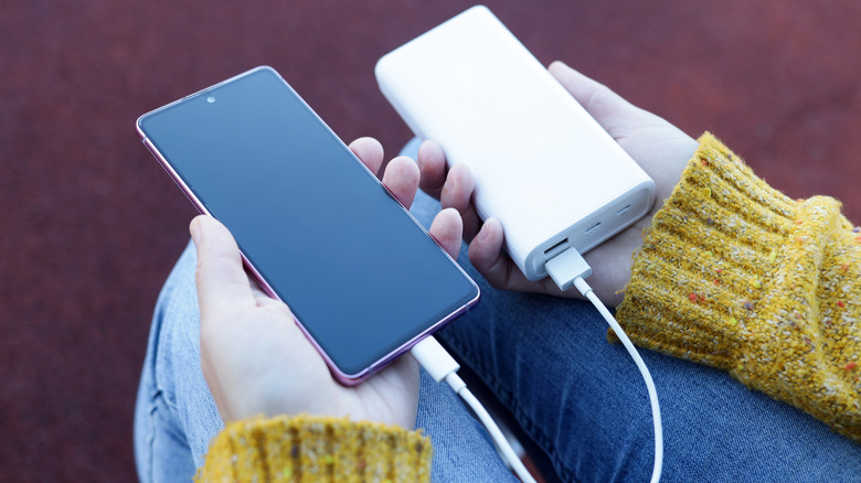 a person charging their phone with a white portable power bank