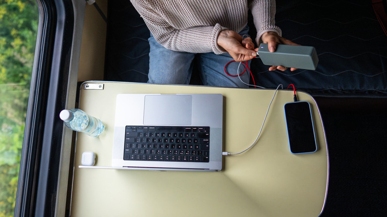 a person charging their laptop on a train with a portable power bank