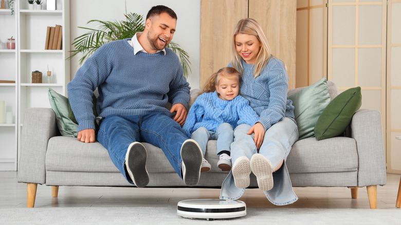 A family watching a robot vacuum go past