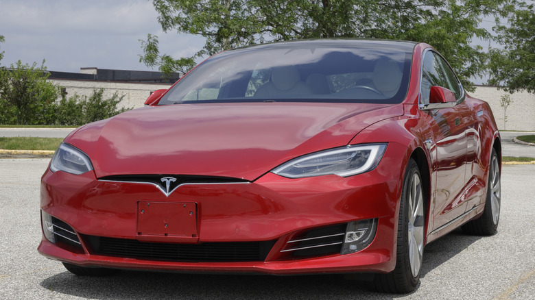 a red Tesla EV parked in a parking lot