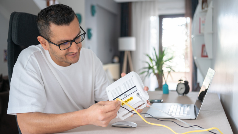 A man connecting an Ethernet cable to a router