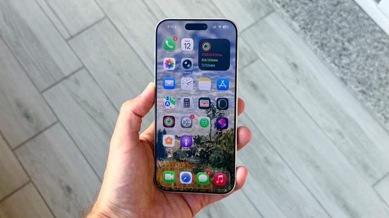 Person holding iPhone 17 Pro Max with iOS 26 home screen