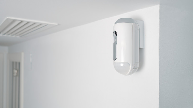 a motion detector mounted on a wall indoors as part of a burglar alarm system