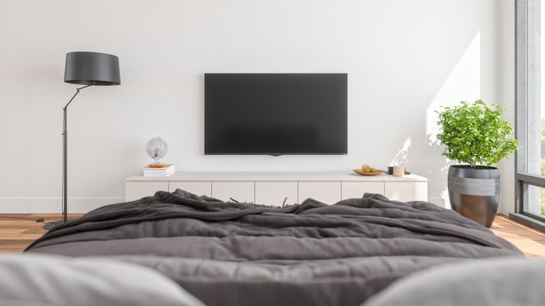 a TV mounted on a wall across from a bed in a bedroom
