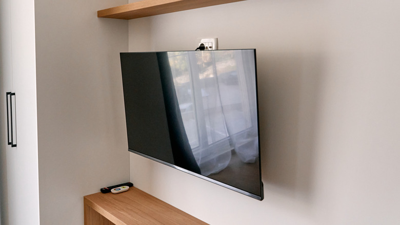 A wall-mounted TV tilted downward while powered off.