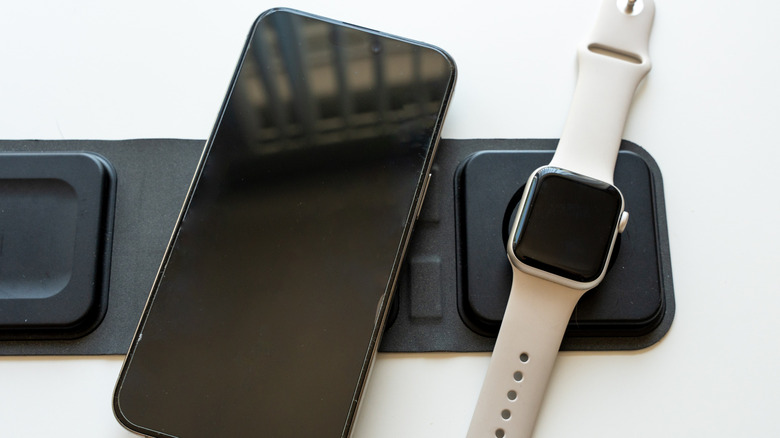 A smartphone and a smartwatch both on a wireless charging dock.