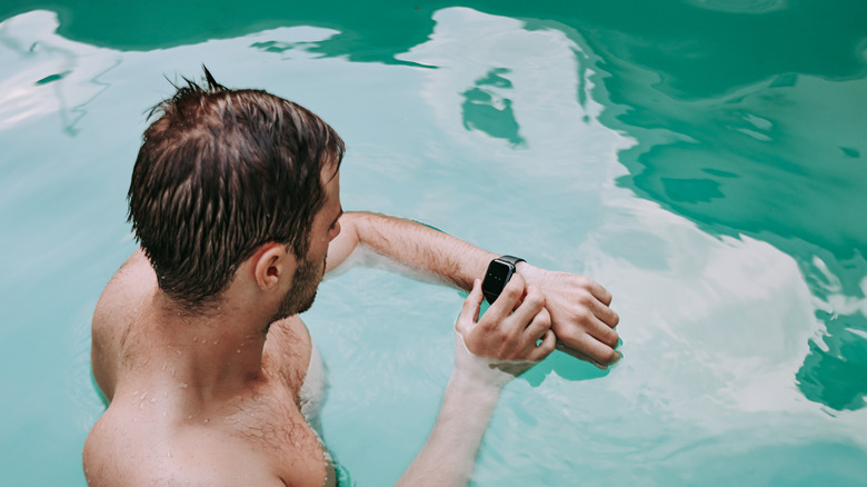 Man in pool using smartwatch