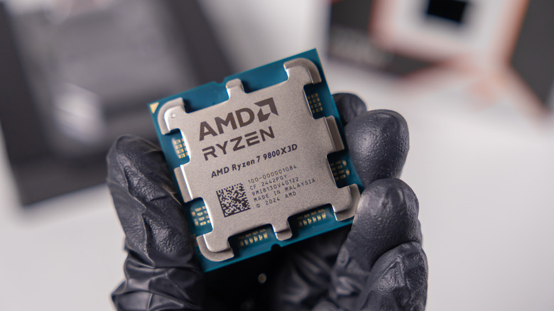 An AMD Ryzen 7 9800X3D processor being held in a gloved hand
