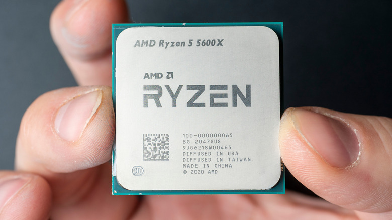 A hand holding an AMD Ryzen 5 5600X processor
