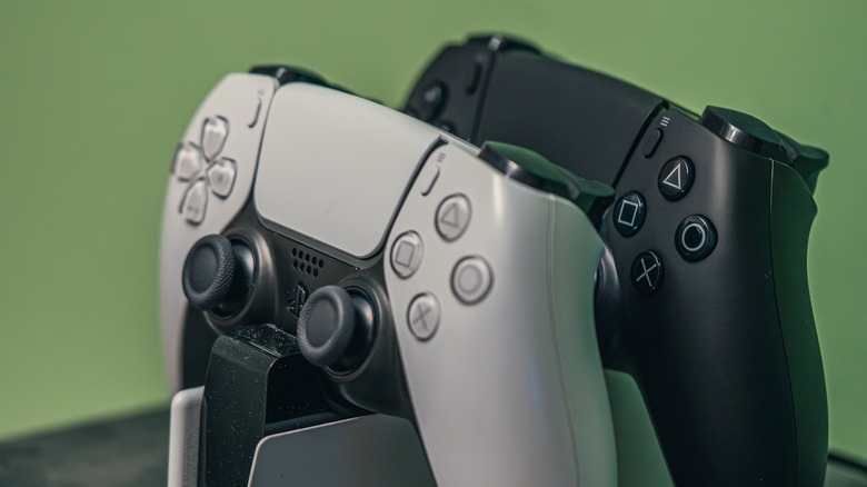 Photo of white and black PlayStation 5 controllers.