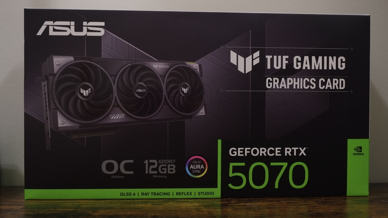 An ASUS TUF Gaming RTX 5070 graphics card box on a wooden surface.