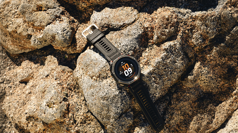 An Amazfit T-Rex Dual Solar smartwatch spread out on rocks.