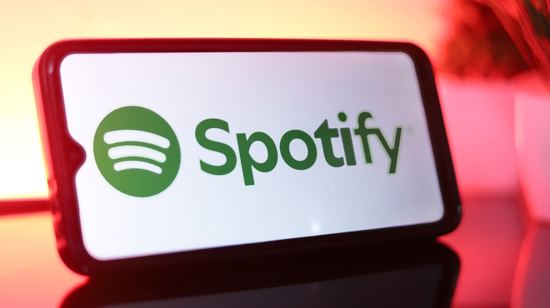 The Spotify logo on a smartphone that's resting on a glass surface.