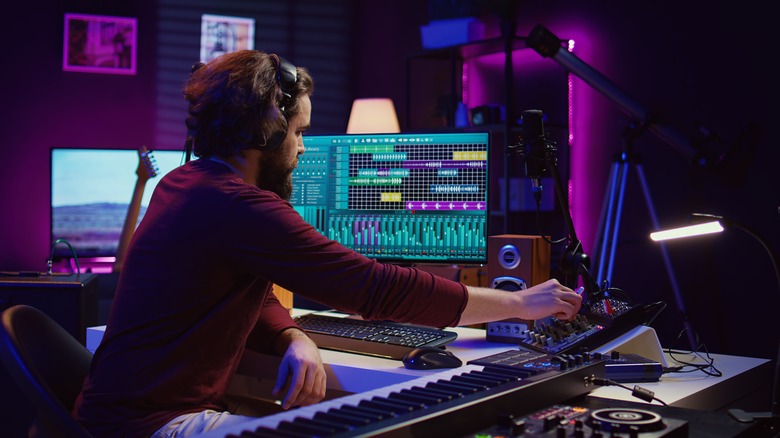 A person sitting at a desk using an audio mixer.