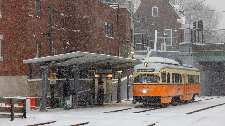 An MBTA trolley serves snowy Milton station on the Mattapan High Speed Line.