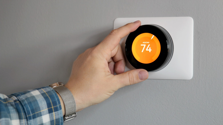 A person adjusting the temperature using a Nest Learning Thermostat.