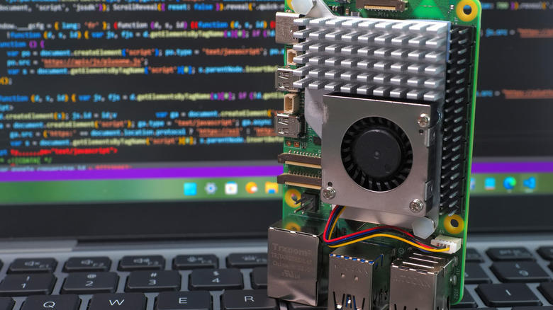Close-up shot of a Raspberry Pi 5 on a laptop keyboard with a fan and heat sink on it.