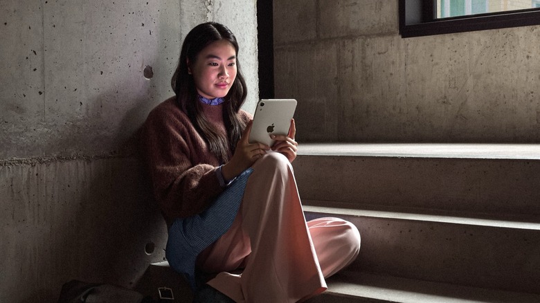 woman using new iPad Mini on staircase in dark environment