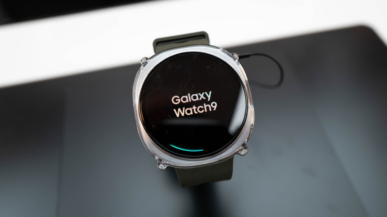 Galaxy Watch 9 sitting on display stand showing logo on screen