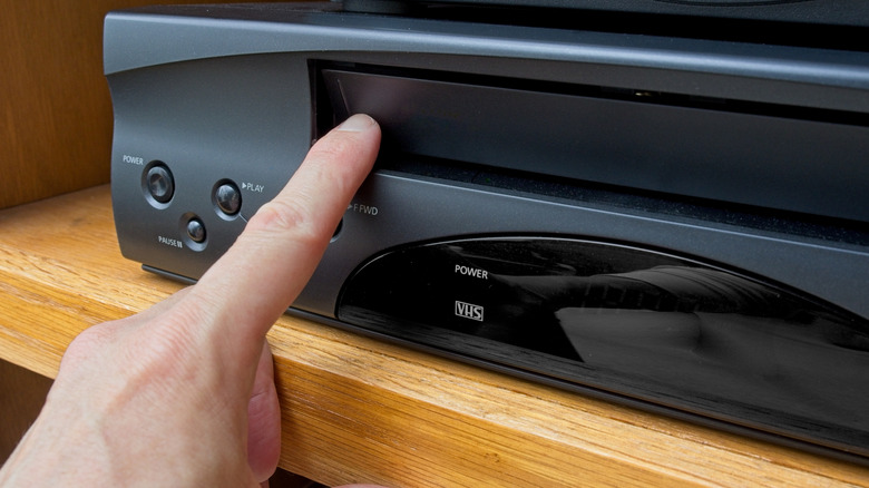 Person touching vintage VCR