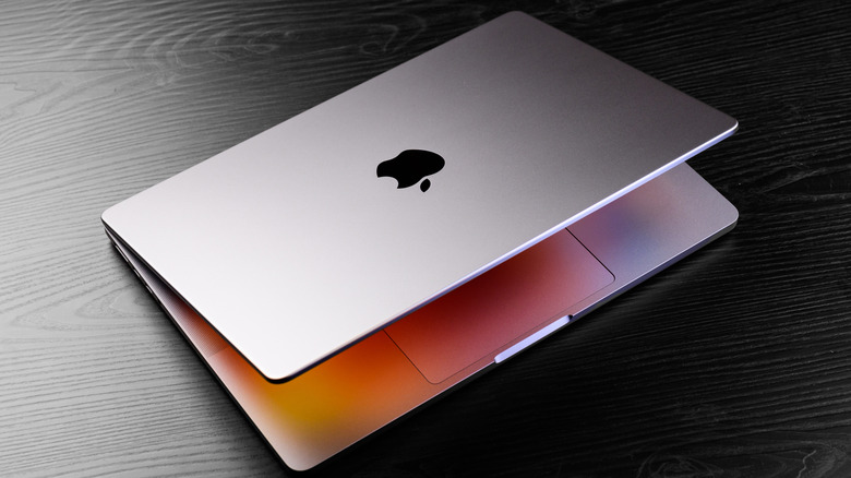 A unibody MacBook laptop on a black desk