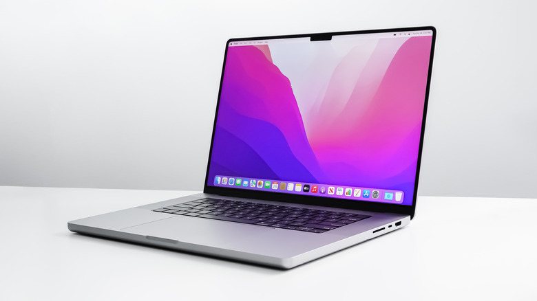 MacBook Pro M1 MAX laptop with a purple heavy desktop background, white table and white wall