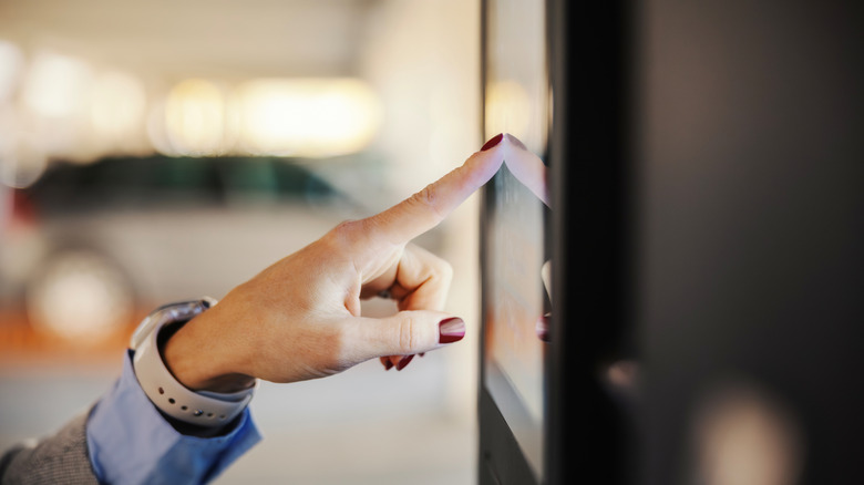 A woman with painted nails touching a computer screen