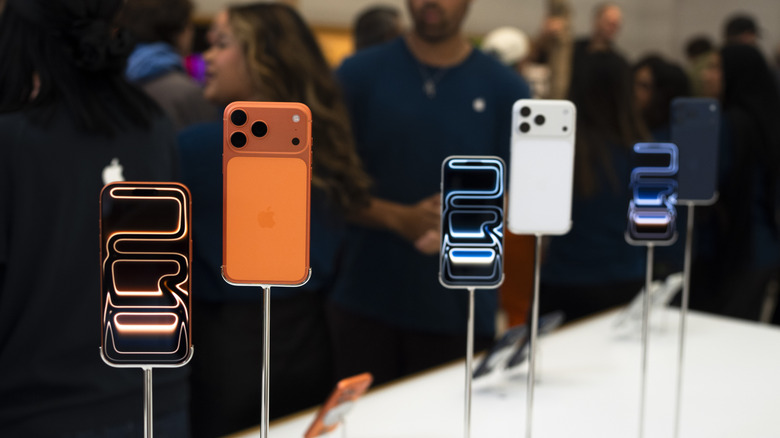 The front and backs of an orange, silver, and blue iPhone 17 Pros displayed on stands during an Apple event