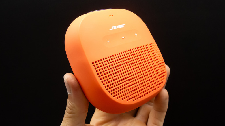 Close-up of a person holding an orange Bose Bluetooth speaker