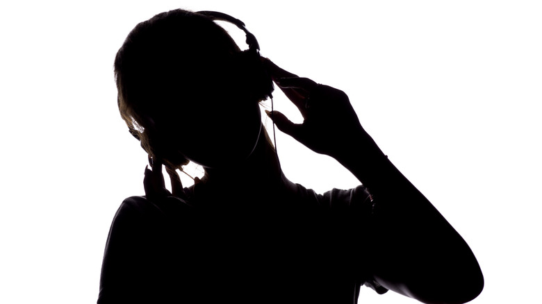 A silhouette of a person using headphones.