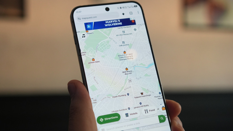 Person holding up a smartphone with MapQuest open.