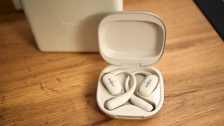 A pair of Shokz open-ear earbuds in their charging case.