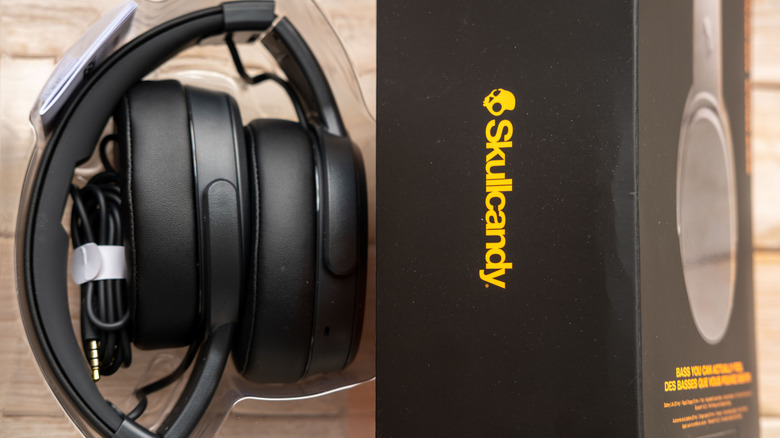 A pair of Skullcandy headphones placed next to its box.