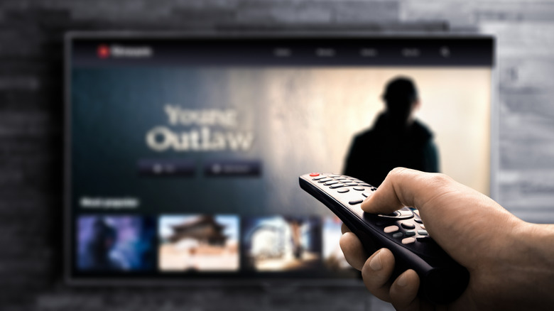 A hand aiming a TV remote at a TV