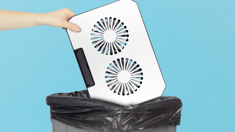 a laptop cooling pad being thrown into a trashcan